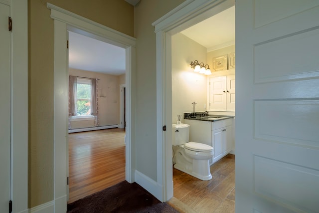 bathroom featuring wood-type flooring, vanity, toilet, and a baseboard heating unit