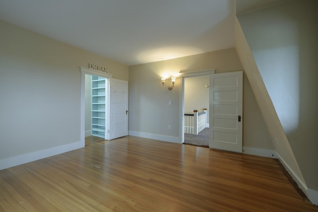 interior space with baseboards, a walk in closet, and wood finished floors