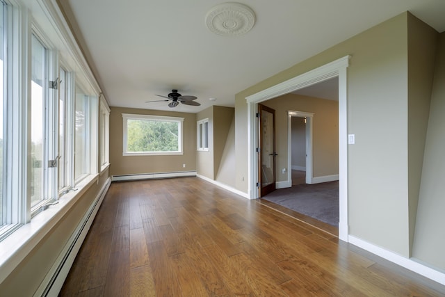 empty room featuring baseboard heating, baseboards, dark wood-style floors, ceiling fan, and a baseboard radiator