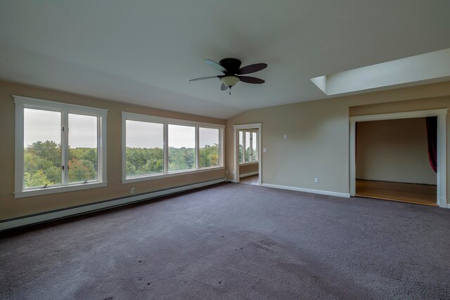 carpeted spare room featuring lofted ceiling with skylight, baseboard heating, ceiling fan, and a wealth of natural light