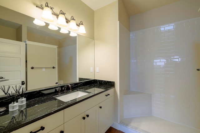 bathroom with a tile shower and vanity