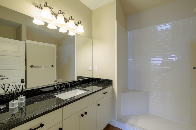 bathroom featuring tiled shower and vanity