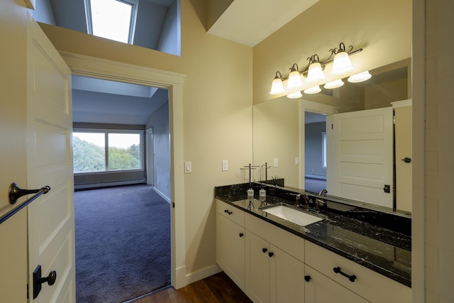 bathroom with a baseboard radiator, vanity, baseboards, and wood finished floors