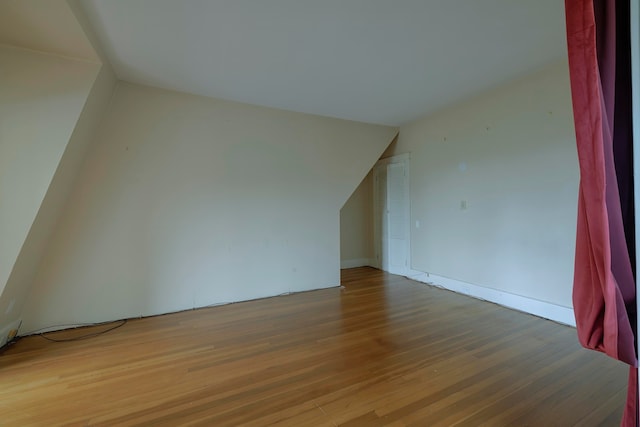 additional living space with light hardwood / wood-style flooring and lofted ceiling