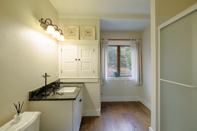 bathroom with toilet, hardwood / wood-style floors, vanity, and baseboards