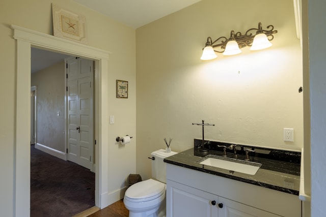 bathroom featuring toilet, vanity, and baseboards