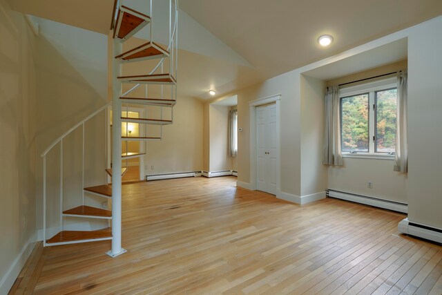 interior space with light hardwood / wood-style flooring, a baseboard heating unit, and vaulted ceiling