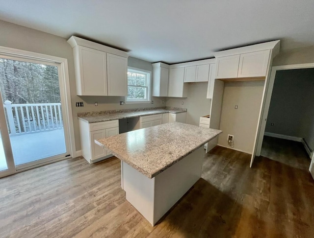 kitchen with light hardwood / wood-style flooring, white cabinetry, light stone countertops, and a kitchen island