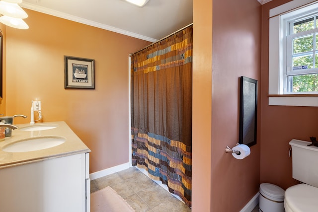 bathroom with double vanity, baseboards, toilet, ornamental molding, and a sink