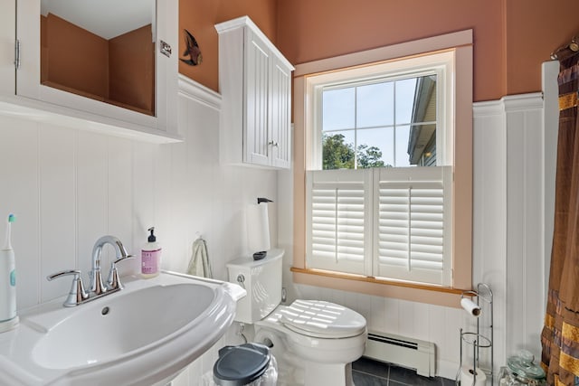 bathroom with a baseboard heating unit, a wainscoted wall, and a sink