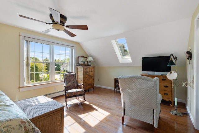 bedroom featuring light wood finished floors, vaulted ceiling with skylight, baseboards, a baseboard radiator, and ceiling fan