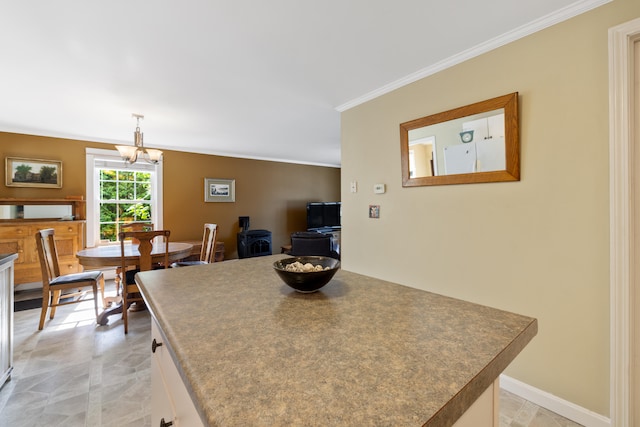 kitchen featuring decorative light fixtures, an inviting chandelier, ornamental molding, white cabinetry, and baseboards