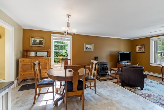 dining space with a chandelier, a wood stove, a healthy amount of sunlight, and crown molding