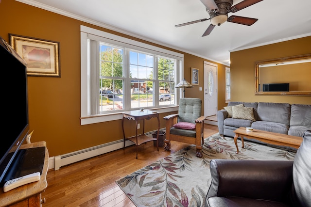 living area with baseboards, a ceiling fan, light wood-style flooring, ornamental molding, and a baseboard heating unit