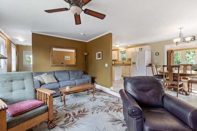 living area with a healthy amount of sunlight, baseboards, ornamental molding, and ceiling fan with notable chandelier