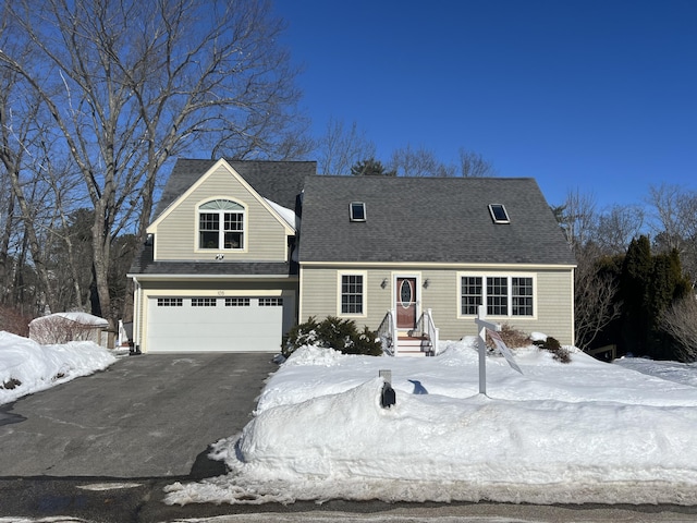 new england style home featuring aphalt driveway, a shingled roof, and an attached garage