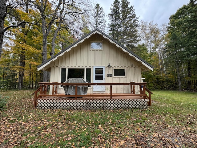 rear view of house featuring a wooden deck and a lawn