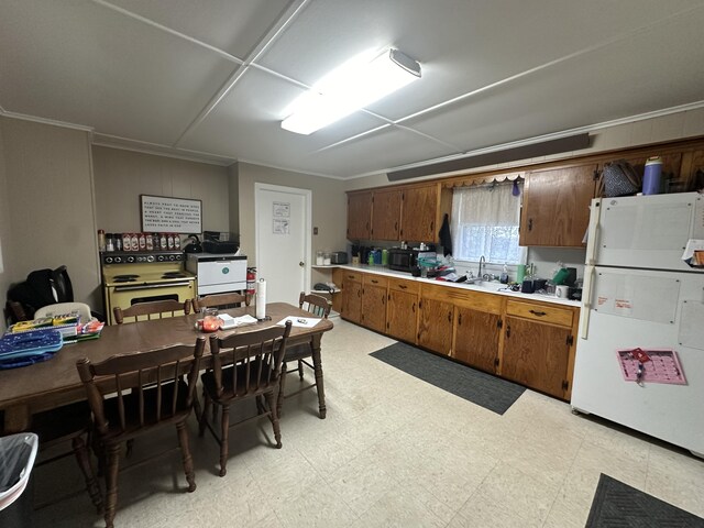 kitchen with ornamental molding, sink, electric range, and white fridge