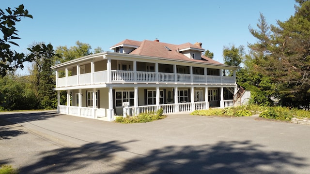 rear view of property with a balcony and covered porch