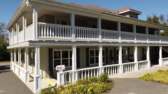 back of property featuring a balcony and a porch