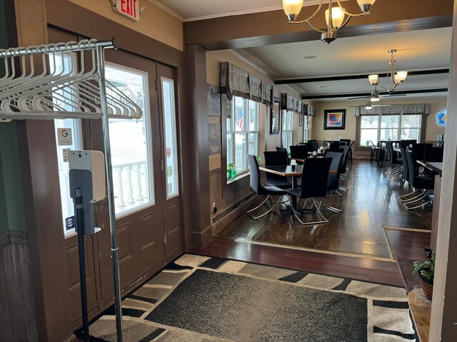 entrance foyer with ornamental molding, a notable chandelier, and dark wood-type flooring