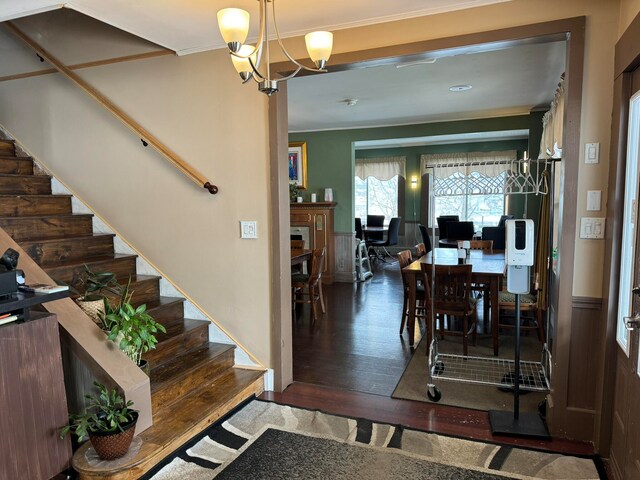 foyer entrance featuring crown molding, dark wood-type flooring, and a chandelier