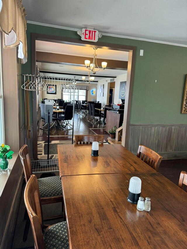 dining room with an inviting chandelier, wood walls, hardwood / wood-style floors, and crown molding