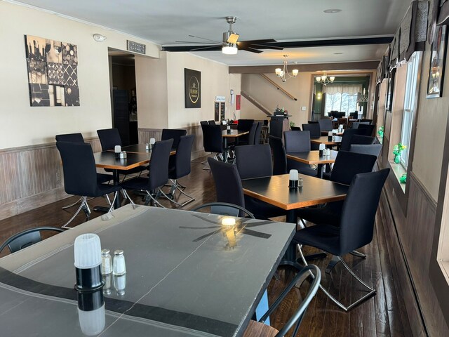 dining space featuring ceiling fan with notable chandelier and dark hardwood / wood-style flooring