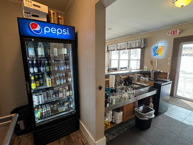 interior space featuring fridge, hardwood / wood-style flooring, ornamental molding, and indoor bar