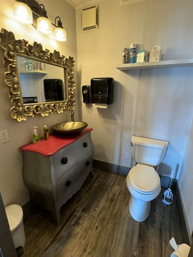 bathroom with vanity, ornamental molding, hardwood / wood-style flooring, and toilet