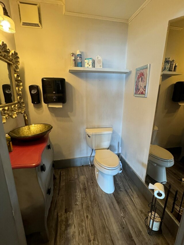 bathroom featuring wood-type flooring, ornamental molding, and toilet