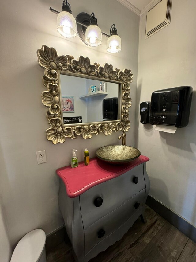 bathroom with vanity, toilet, hardwood / wood-style floors, and crown molding