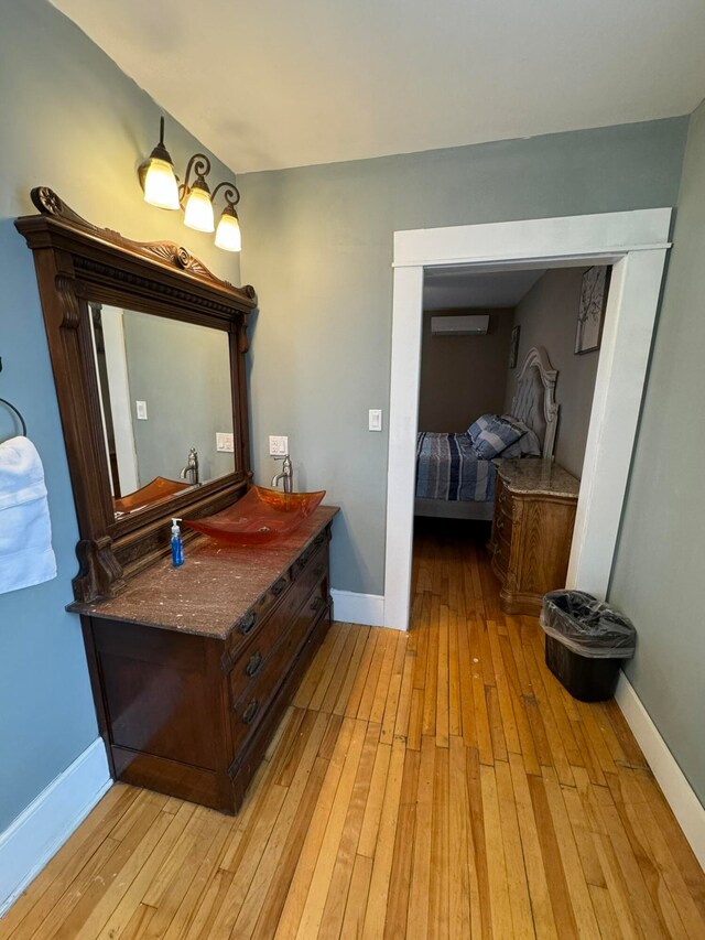 bathroom featuring wood-type flooring, a wall unit AC, and vanity