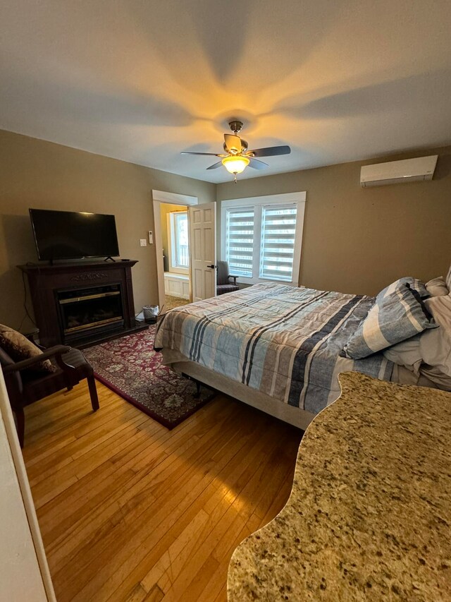 bedroom featuring ceiling fan, hardwood / wood-style floors, and a wall mounted AC