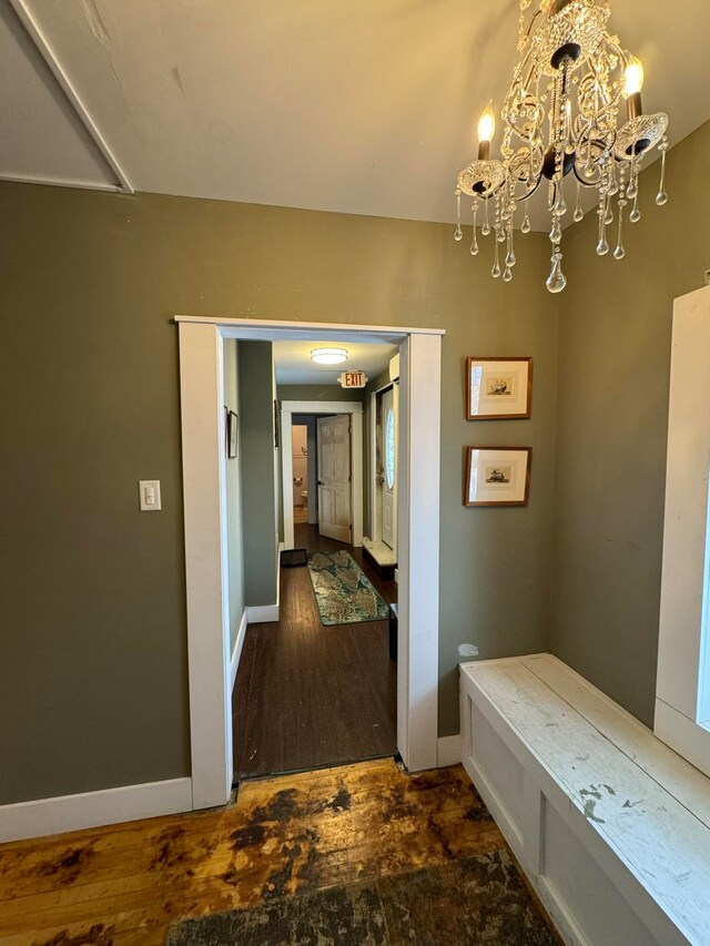 hall with dark hardwood / wood-style floors and a notable chandelier