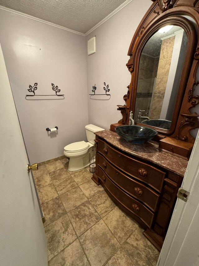 bathroom featuring ornamental molding, a textured ceiling, vanity, and toilet