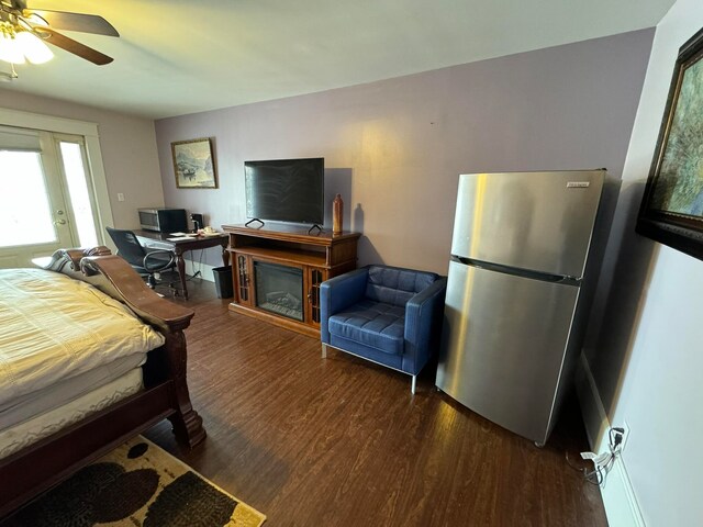 bedroom with dark hardwood / wood-style flooring, ceiling fan, and stainless steel refrigerator