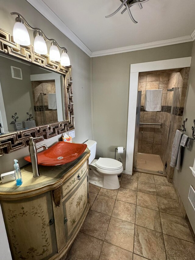 bathroom featuring ornamental molding, vanity, toilet, and a shower with door