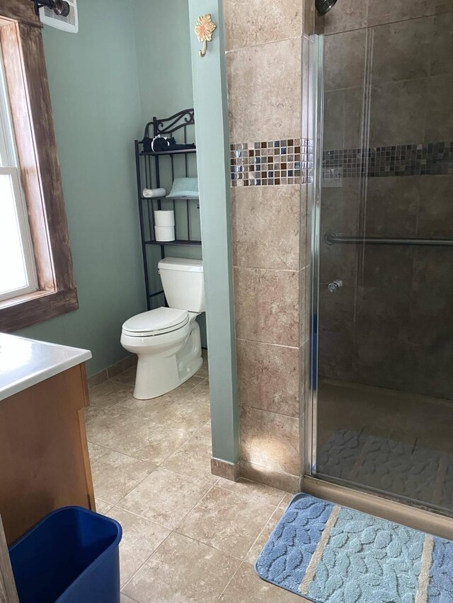 bathroom with walk in shower, vanity, toilet, and tile patterned floors