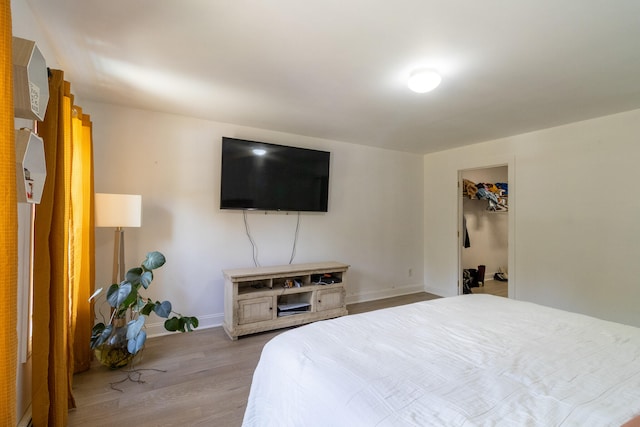 bedroom featuring a spacious closet, light hardwood / wood-style flooring, and a closet