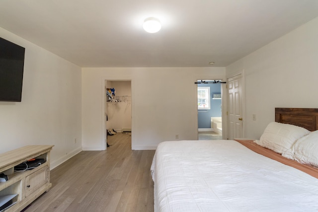 bedroom with light hardwood / wood-style flooring, connected bathroom, a closet, and a walk in closet