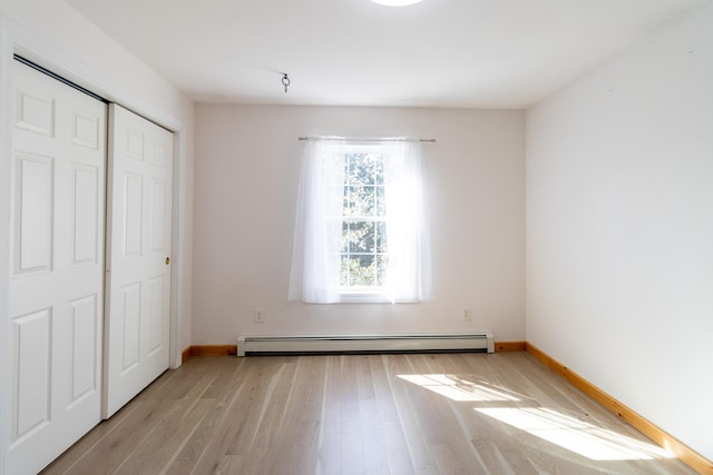 unfurnished bedroom with baseboard heating, light wood-type flooring, and a closet