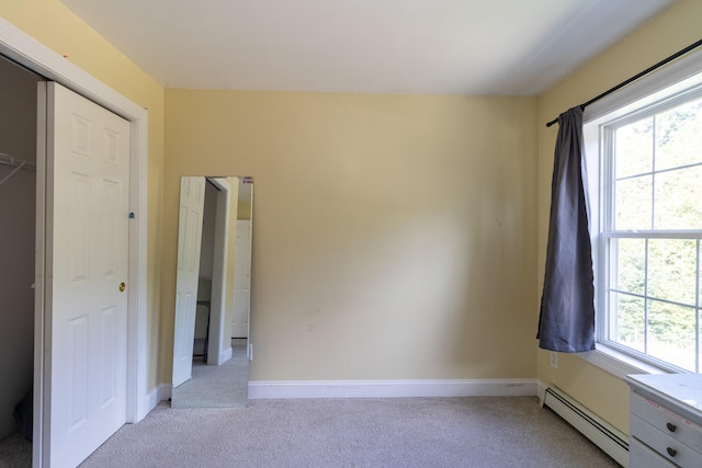 unfurnished bedroom with light carpet, a closet, multiple windows, and a baseboard heating unit