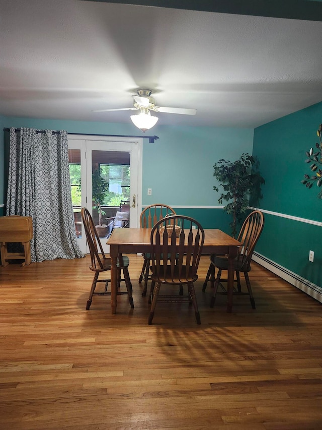 dining area featuring wood-type flooring, ceiling fan, and a baseboard radiator