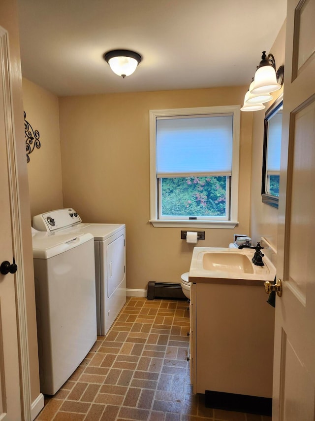 laundry area with a baseboard radiator, sink, and washing machine and dryer