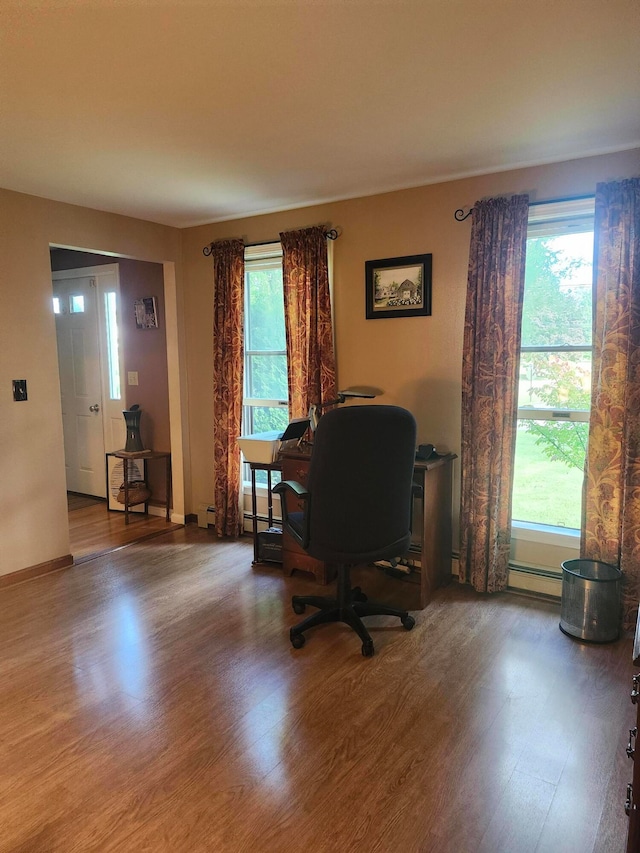 office area featuring a baseboard heating unit and wood-type flooring