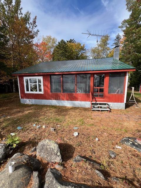 rear view of house with a sunroom, metal roof, crawl space, and a chimney