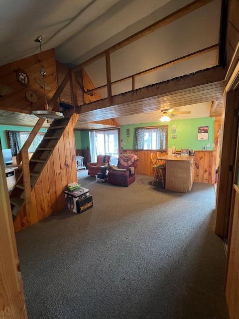 bonus room with wood walls, a towering ceiling, carpet, and stairway