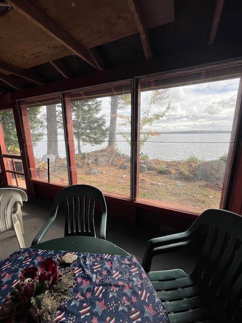 sunroom / solarium with outdoor dining area and a water view