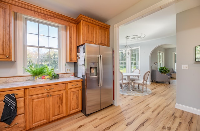 kitchen with pendant lighting, light wood-type flooring, tile countertops, and stainless steel fridge with ice dispenser